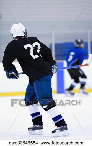Rear view of two ice hockey players playing ice hockey View Large Photo Image Picture - Rear view of two ice hockey players playing ice hockey. Fotosearch