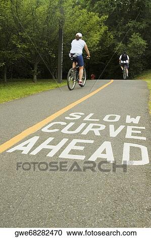 Rear view of two people cycling on the road View Large Photo Image Stock Image - Rear view of two people cycling on the road. Fotosearch
