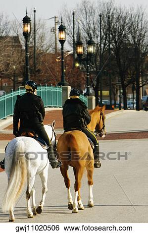 Stock Photograph - Rear view of two people riding horses, Baltimore, Maryland, USA. Fotosearch