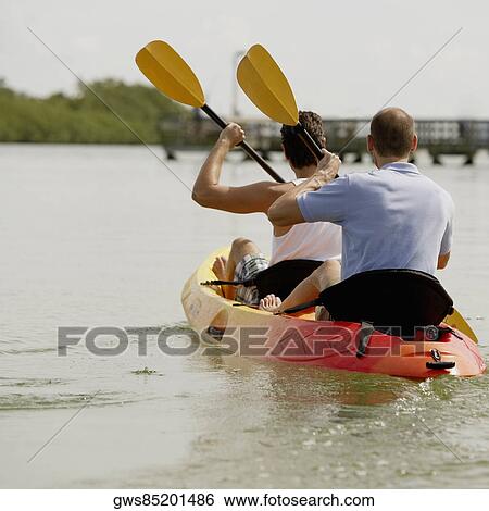Stock Photograph - Rear view of two young men kayaking. Fotosearch