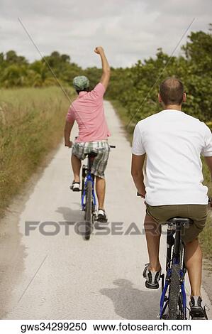 Rear view of two young men riding bicycles View Large Photo Image Stock Image - Rear view of two young men riding bicycles. Fotosearch