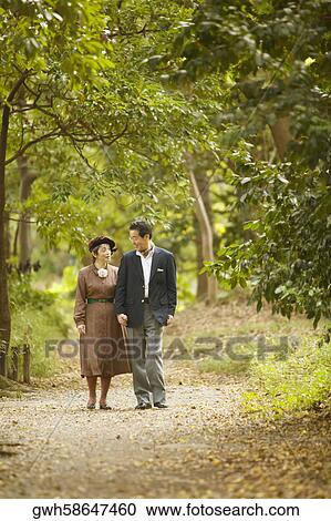 Senior man and a mature woman walking in the park View Large Photo Image Stock Image - Senior man and a mature woman walking in the park . Fotosearch