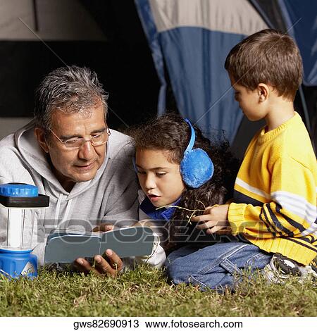 Side profile of a boy looking at his grandfather and sister reading a book View Large Photo Image Stock Image - Side profile of a boy looking at his grandfather and sister reading a book. Fotosearch