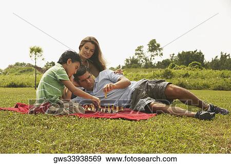 Stock Photo - Side profile of a boy sitting with his parents and playing chess. Fotosearch