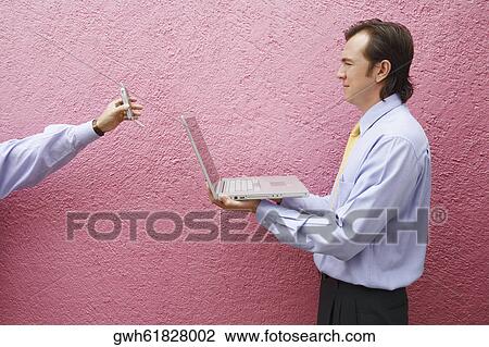 Side profile of a businessman holding a laptop with a person's hand holding a mobile phone View Large Photo Image Stock Image - Side profile of a businessman holding a laptop with a person's hand holding a mobile phone. Fotosearch