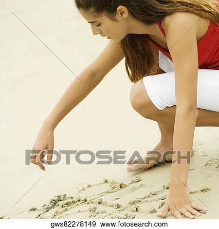 Side profile of a girl writing in sand View Large Photo Image Stock Photo - Side profile of a girl writing in sand. Fotosearch