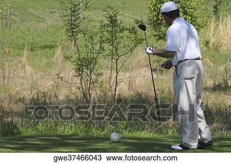 Side profile of a man holding a golf club View Large Photo Image Stock Image - Side profile of a man holding a golf club. Fotosearch