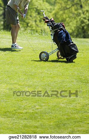 Stock Photo - Side profile of a man swinging a golf club. Fotosearch