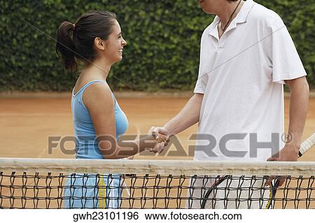 Side profile of a mid adult man and a young woman shaking hands on a tennis court View Large Photo Image Stock Photograph - Side profile of a mid adult man and a young woman shaking hands on a tennis court. Fotosearch