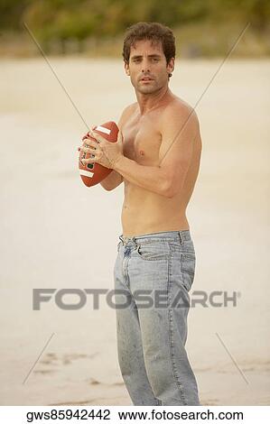 Side profile of a mid adult man holding a rugby ball on the beach View Large Photo Image Stock Image - Side profile of a mid adult man holding a rugby ball on the beach. Fotosearch