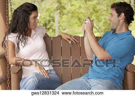 Side profile of a mid adult man photographing a young woman View Large Photo Image Picture - Side profile of a mid adult man photographing a young woman. Fotosearch