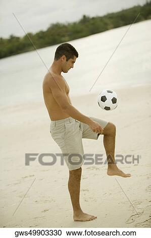 Side profile of a mid adult man playing with a soccer ball on the beach View Large Photo Image Stock Image - Side profile of a mid adult man playing with a soccer ball on the beach. Fotosearch