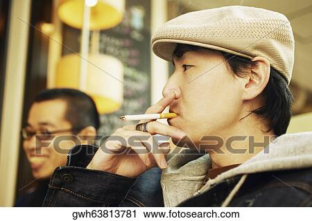 Side profile of a mid adult man smoking a cigarette and a young man smiling beside him View Large Photo Image Stock Image - Side profile of a mid adult man smoking a cigarette and a young man smiling beside him. Fotosearch