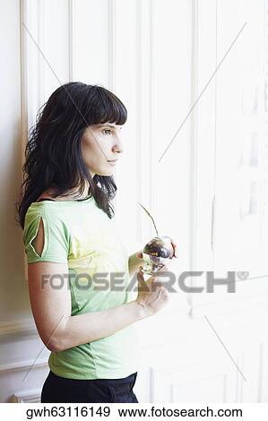 Stock Photo - Side profile of a mid adult woman holding a glass. Fotosearch