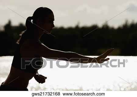 Stock Photo - Side profile of a mid adult woman exercising on the beach. Fotosearch