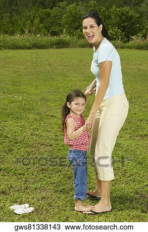 Stock Image - Side profile of a mother and her daughter smiling. Fotosearch