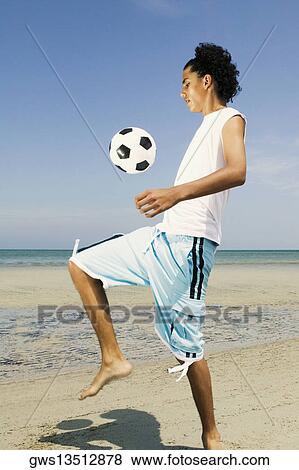 Side profile of a teenage boy playing with a soccer ball on the beach View Large Photo Image Stock Photo - Side profile of a teenage boy playing with a soccer ball on the beach. Fotosearch