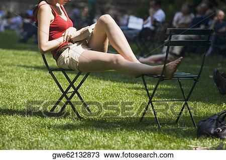 Side profile of a woman sitting on a chair in the park View Large Photo Image Stock Image - Side profile of a woman sitting on a chair in the park. Fotosearch
