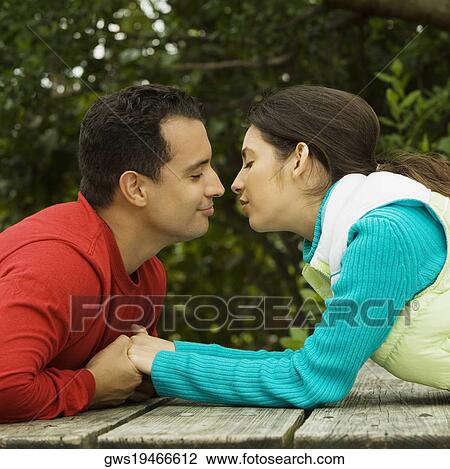 Side profile of a young couple holding hands and kissing View Large Photo Image Stock Image - Side profile of a young couple holding hands and kissing. Fotosearch