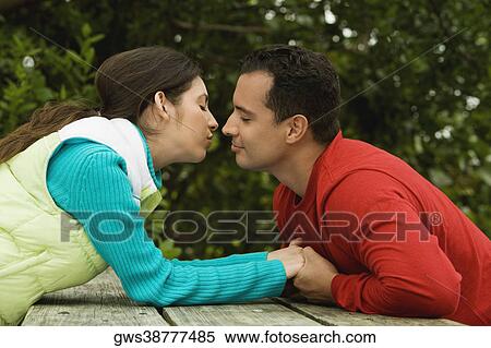 Side profile of a young couple holding hands and kissing View Large Photo Image Stock Photography - Side profile of a young couple holding hands and kissing. Fotosearch