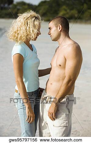 Side profile of a young couple looking at each other View Large Photo Image Stock Photograph - Side profile of a young couple looking at each other. Fotosearch