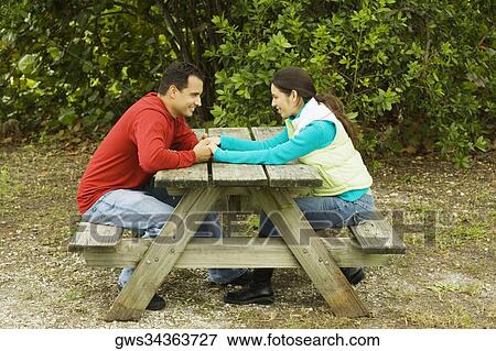 Side profile of a young couple sitting and holding hands View Large Photo Image Stock Photo - Side profile of a young couple sitting and holding hands. Fotosearch