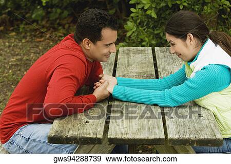 Stock Photo - Side profile of a young couple sitting and holding hands. Fotosearch