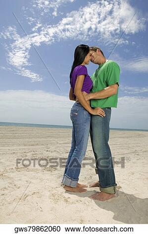 Side profile of a young couple embracing each other on the beach View Large Photo Image Stock Image - Side profile of a young couple embracing each other on the beach. Fotosearch