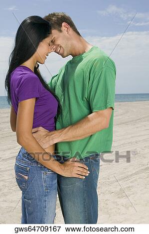 Side profile of a young couple embracing each other View Large Photo Image Stock Photo - Side profile of a young couple embracing each other. Fotosearch