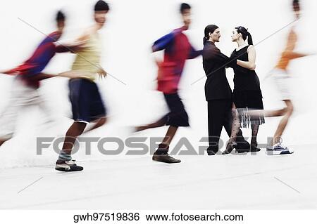 Stock Photograph - Side profile of a young couple tangoing with four boys running in front of them. Fotosearch