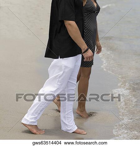 Side profile of a young couple walking on the beach View Large Photo Image Picture - Side profile of a young couple walking on the beach. Fotosearch