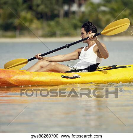 Stock Image - Side profile of a young man kayaking. Fotosearch