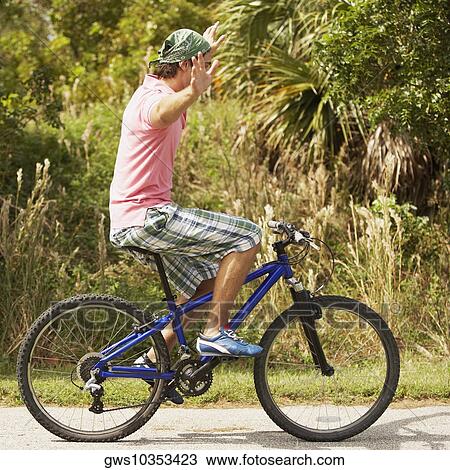 Stock Image - Side profile of a young man performing tricks on a bicycle. Fotosearch