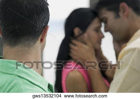 Side profile of a young man with a young woman and a mid adult man embracing each other in the background View Large Photo Image Picture - Side profile of a young man with a young woman and a mid adult man embracing each other in the background. Fotosearch
