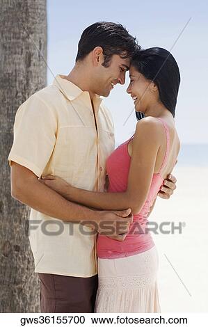 Side profile of a young woman and a mid adult man embracing each other and smiling View Large Photo Image Stock Image - Side profile of a young woman and a mid adult man embracing each other and smiling. Fotosearch
