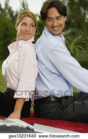 Side profile of a young woman and a mid adult man sitting back to back View Large Photo Image Stock Photo - Side profile of a young woman and a mid adult man sitting back to back. Fotosearch