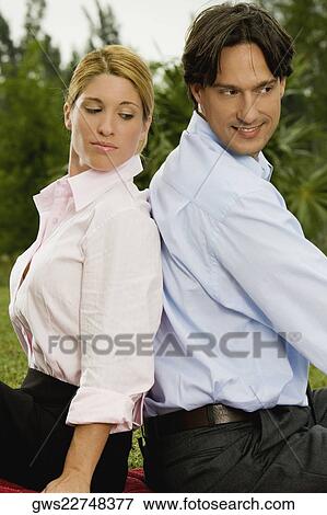 Side profile of a young woman and a mid adult man sitting back to back View Large Photo Image Stock Photo - Side profile of a young woman and a mid adult man sitting back to back. Fotosearch