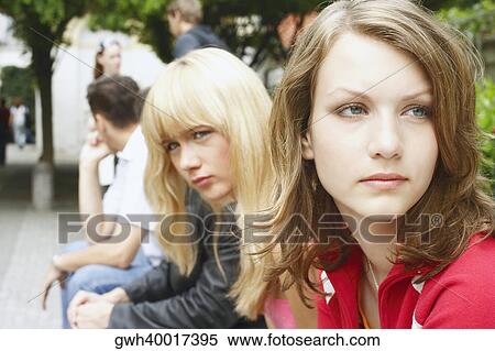 Stock Photography - Side profile of a young woman and a teenage girl sitting. Fotosearch