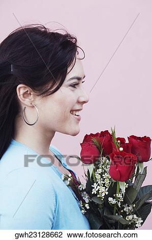 Side profile of a young woman holding a bouquet of flowers View Large Photo Image Stock Image - Side profile of a young woman holding a bouquet of flowers. Fotosearch