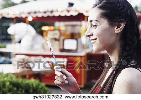 Side profile of a young woman holding a lollipop View Large Photo Image Stock Image - Side profile of a young woman holding a lollipop . Fotosearch