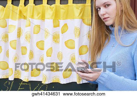 Stock Image - Side profile of a young woman holding a personal data assistant. Fotosearch