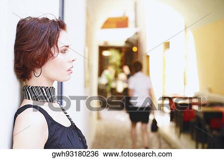 Stock Photograph - Side profile of a young woman leaning against a wall . Fotosearch