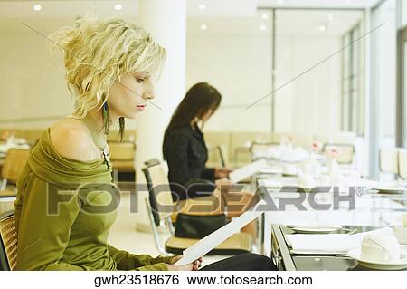 Side profile of a young woman sitting in a restaurant and holding a menu card View Large Photo Image Stock Photograph - Side profile of a young woman sitting in a restaurant and holding a menu card . Fotosearch