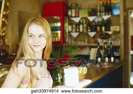 Side profile of a young woman smiling at a bar counter View Large Photo Image Picture - Side profile of a young woman smiling at a bar counter . Fotosearch