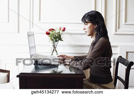 Stock Photo - Side profile of a young woman using a laptop. Fotosearch