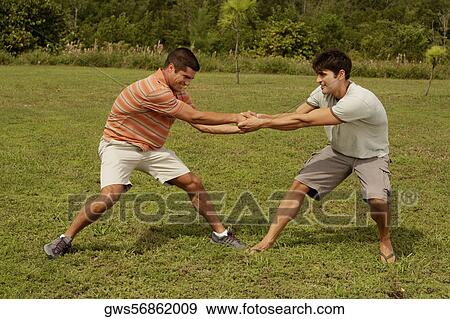Stock Photo - Side profile of two mid adult men playing. Fotosearch