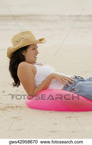 Side profile of young woman lying on an inflatable ring at the beach View Large Photo Image Stock Image - Side profile of young woman lying on an inflatable ring at the beach. Fotosearch