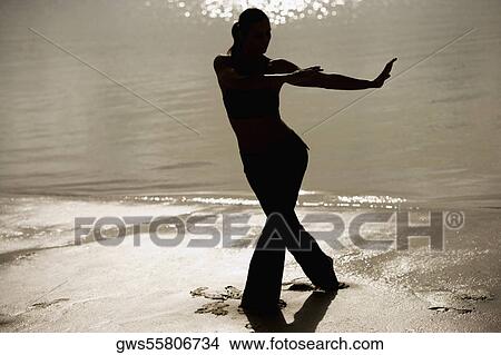 Silhouette of a mid adult woman exercising on the beach View Large Photo Image Picture - Silhouette of a mid adult woman exercising on the beach. Fotosearch