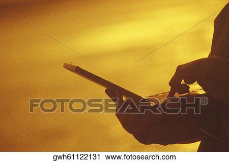 Stock Image - Silhouette of a person using a laptop. Fotosearch