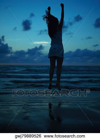 Silhouette of a teenage girl jumping on the beach at dusk View Large Photo Image Stock Photograph - Silhouette of a teenage girl jumping on the beach at dusk. Fotosearch